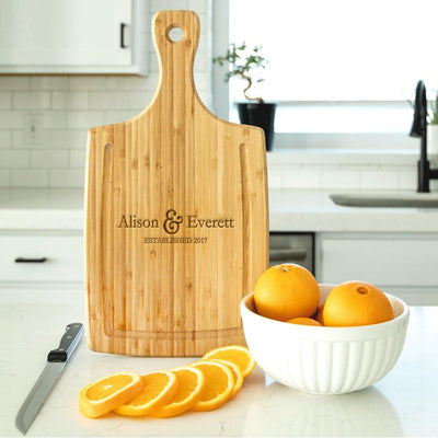 https://www.agiftpersonalized.com/cdn/shop/products/staged_QUAL1172LargeHandledCuttingboardwithJuiceGrooves_stagedonwhitequartzcounterstandingwithoranges_Ampersand_squarecrop_400x.jpg?v=1642141360